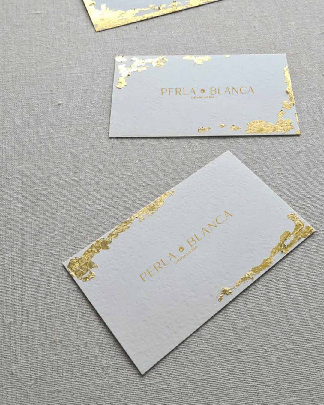 bigliettini da visita bianchi con foglia oro per brand elegante - progetto di comunicazione e pubblicità per champagne bar elegante in malaga - agenzia specializzata in loghi e pubblicità social a Napoli - 